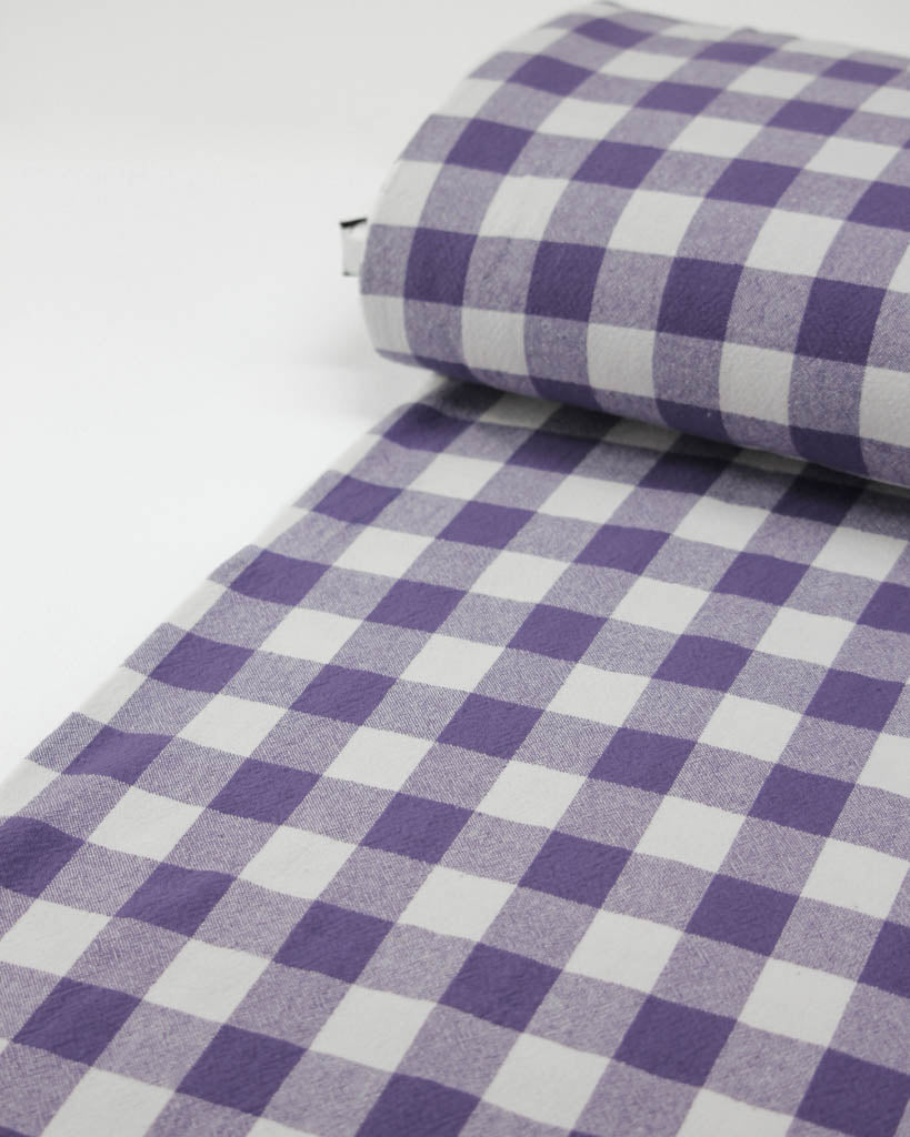 Roll of purple and white checkered fabric on a white background