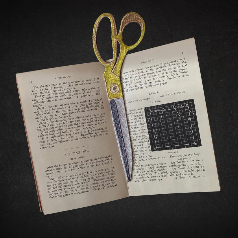 Scissors on an open book with text and diagrams