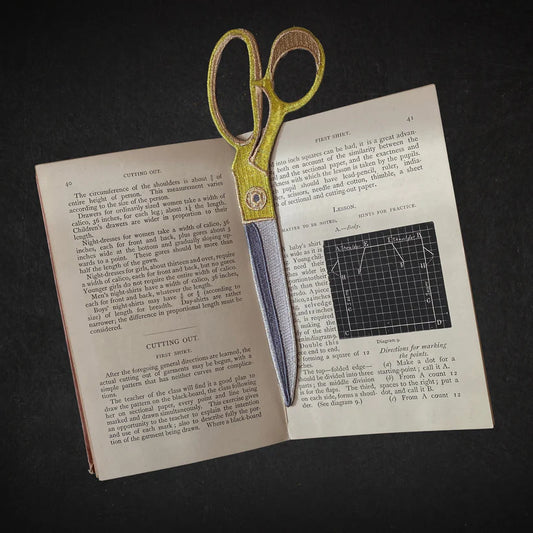 Scissors on an open book with text and diagrams