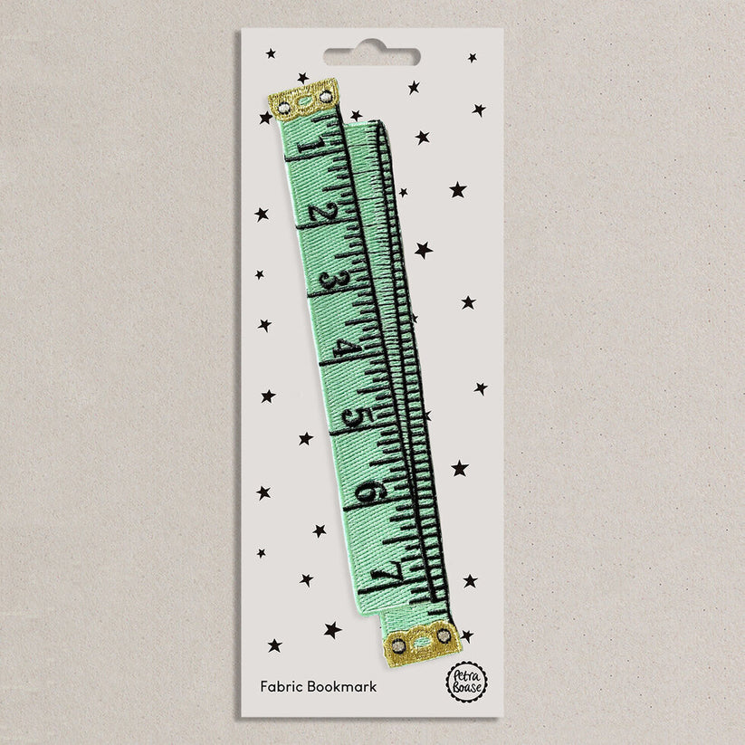 Fabric bookmark shaped like a mint green tape measure on a white presentation card 