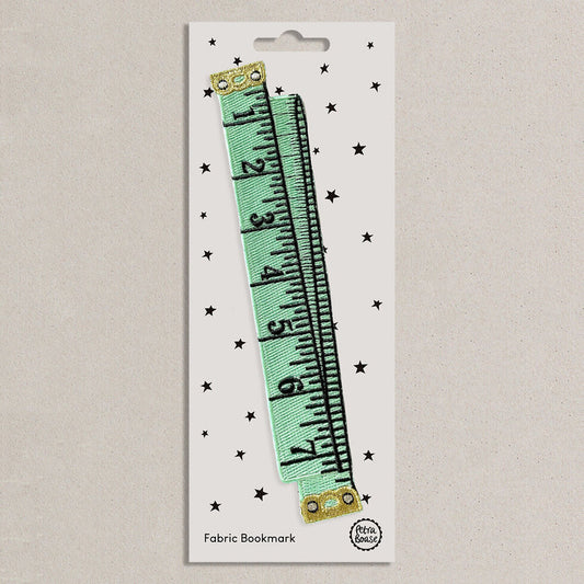 Fabric bookmark shaped like a mint green tape measure on a white presentation card 