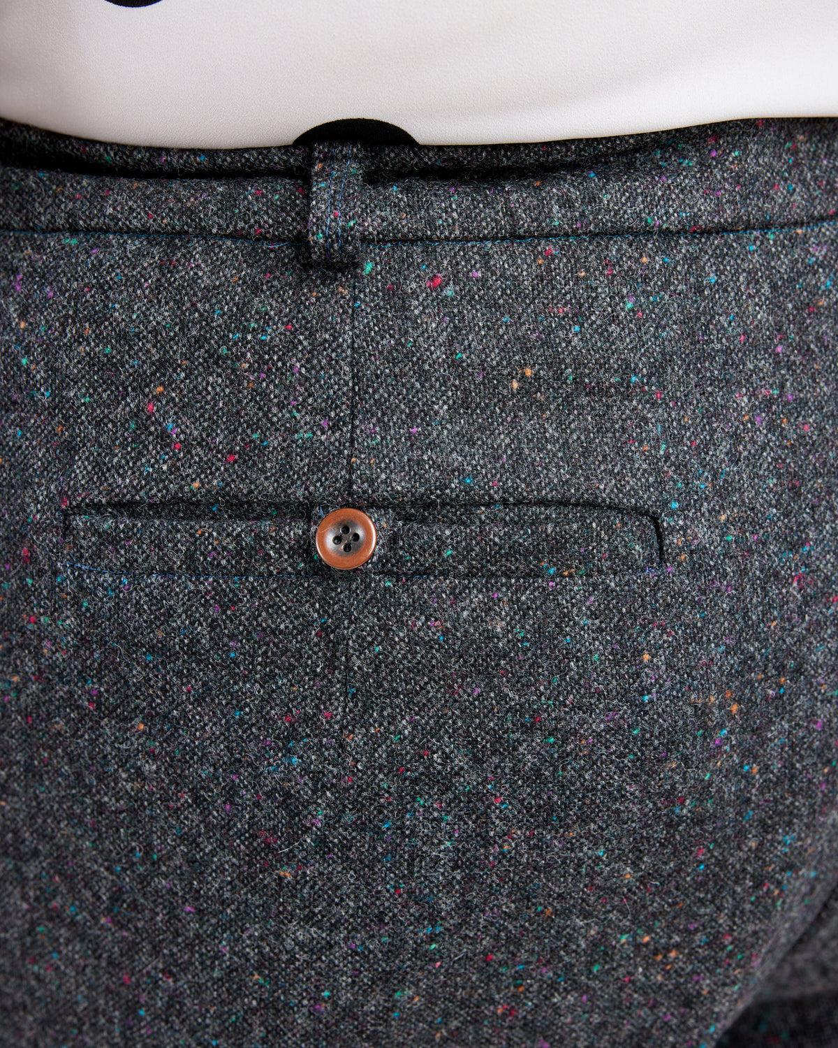 Close-up of a gray textured fabric with a button on a white background. These pants are the Meriam Trousers sewing pattern from Cashmerette.