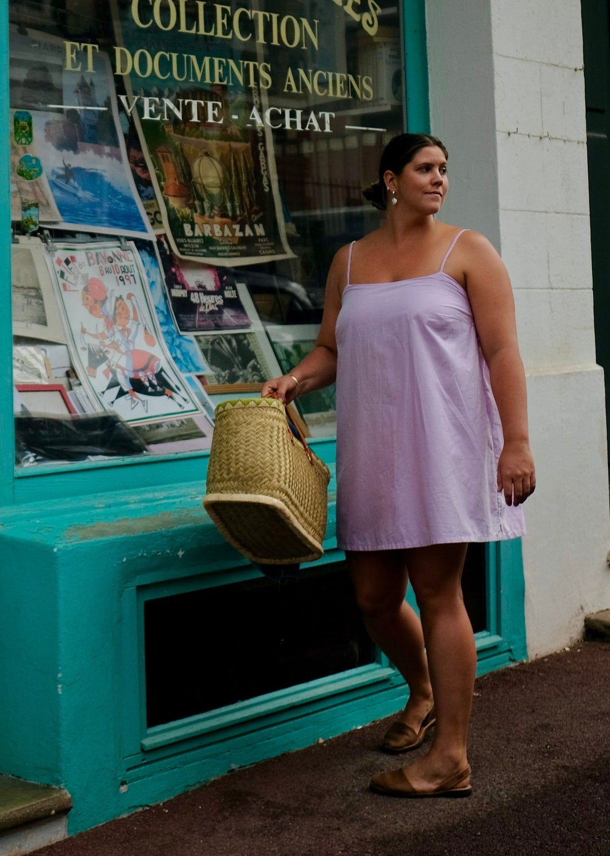 Woman in a pink dress standing in front of a store with a turquoise facade.