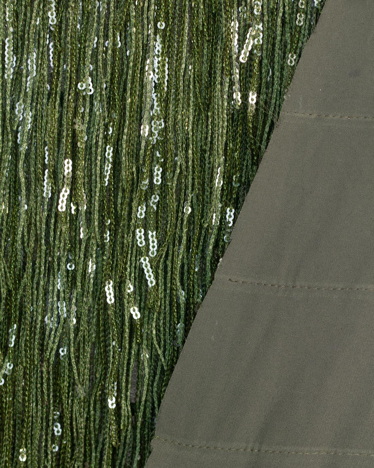 Close-up of a dark olive green sequined tassel fabric with vertical strands of sequins, folded to show its underside.