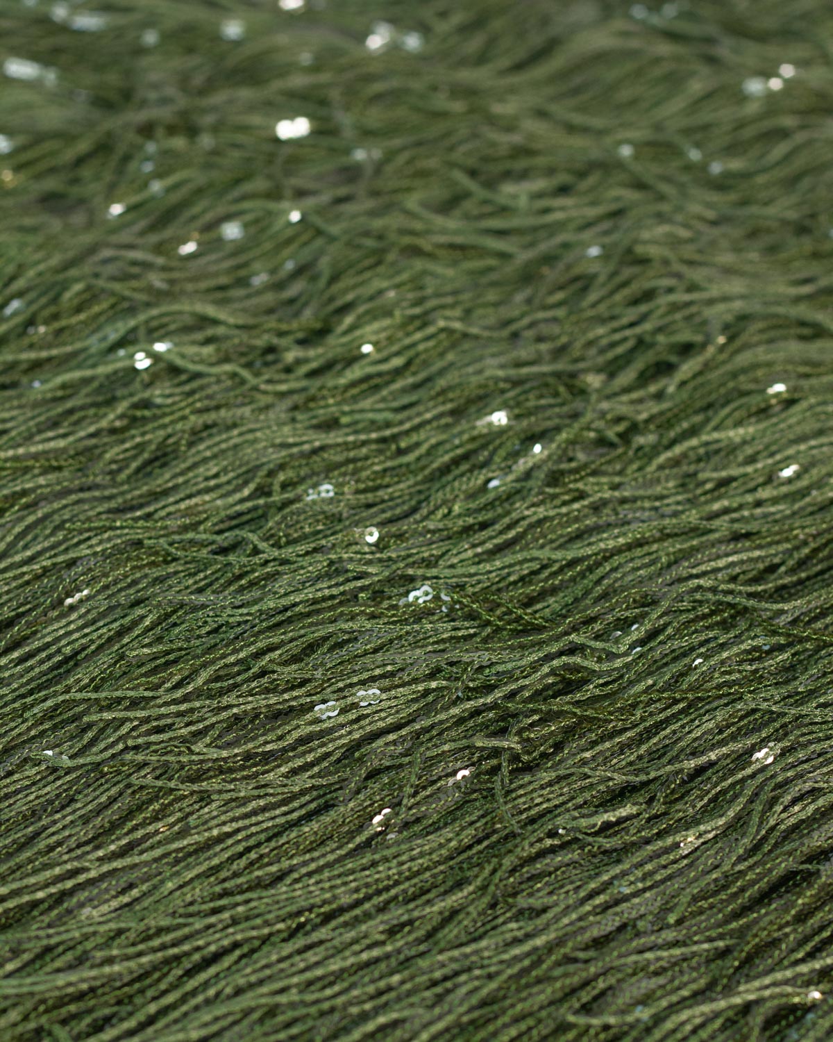 Close-up of olive green polyester sequin tassel fabric.