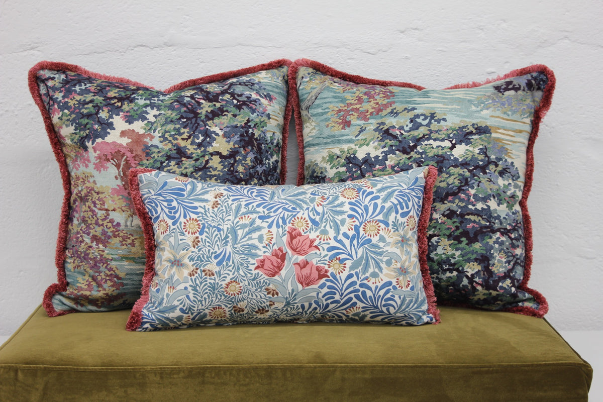 Handcrafted patterned cushions with contrasting trim on a velvet window seat