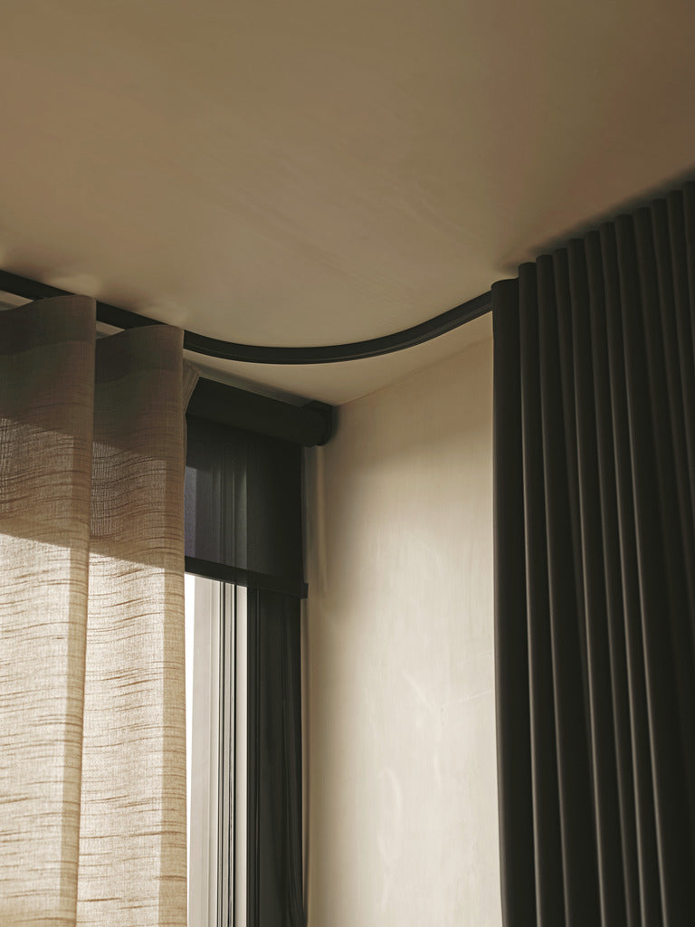 Curved black curtain track installed at a window