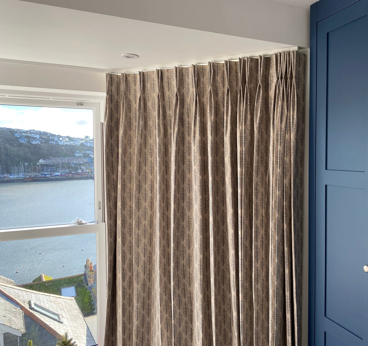 Fitted patterned curtains beside a window and blue cabinetry