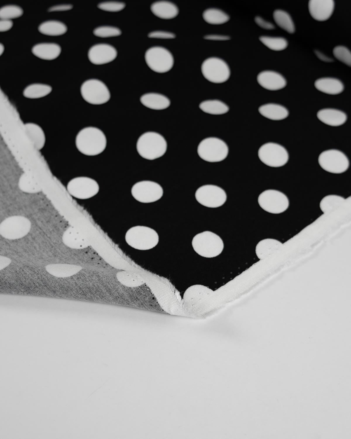 A close-up of a black viscose twill  fabric  with a white polka dot pattern .