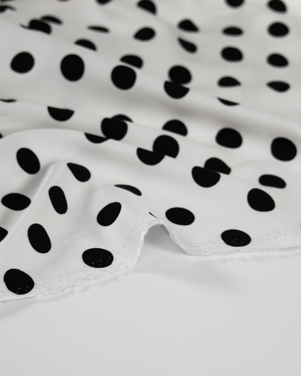 White viscose fabric with a black polka dot pattern.