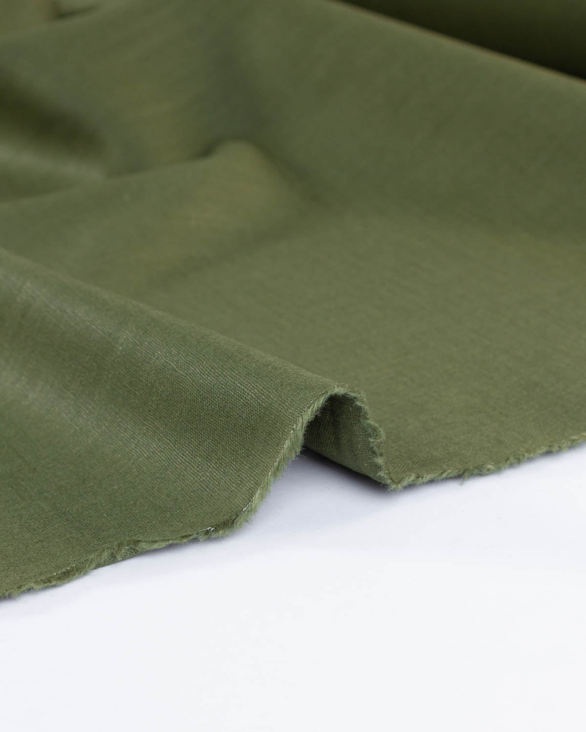 Edge of olive green linen fabric showing the thickness and mid weight